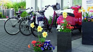Um hotel chamado "HOTEL ELYSEE" com bicicletas estacionadas na frente e jardineiras de flores.