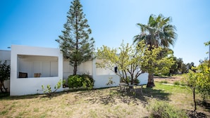 A modern white building with a balcony, surrounded by trees and a grassy area. - Fotini Studios (Kos)