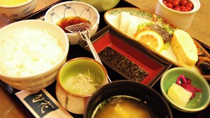 Un repas japonais traditionnel composé de riz, de soupe et de divers plats, notamment du poisson, des légumes et des aliments marinés.