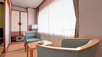 A room with a sofa, a small table, a television, and a wardrobe.