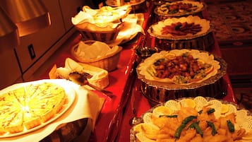 A buffet table with various dishes, including a large pie, bowls of food, and a variety of side dishes.