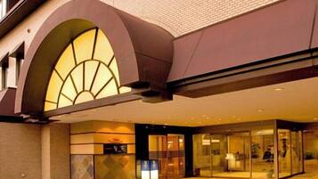 A hotel entrance with a modern design, featuring a curved archway and a glass facade.