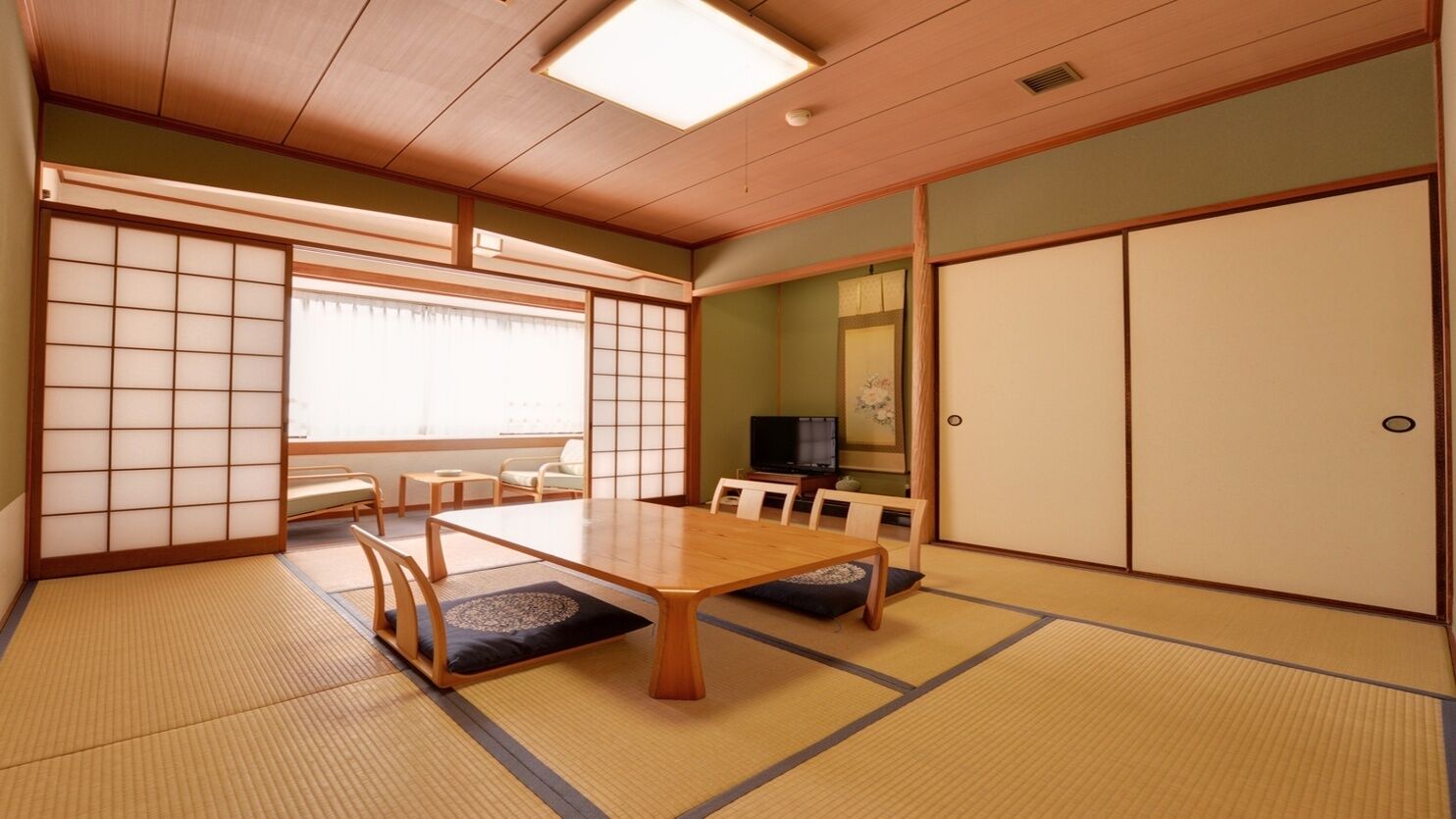 Una habitació japonesa tradicional amb tatami, una taula baixa, portes corredisses i una televisió.