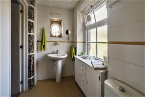 Ein kleines Badezimmer mit einem weißen Waschbecken, einem Spiegel, einem Fenster und einem Handtuchhalter.