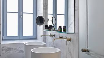 A bathroom with two sinks, a mirror, and a shelf with toiletries.