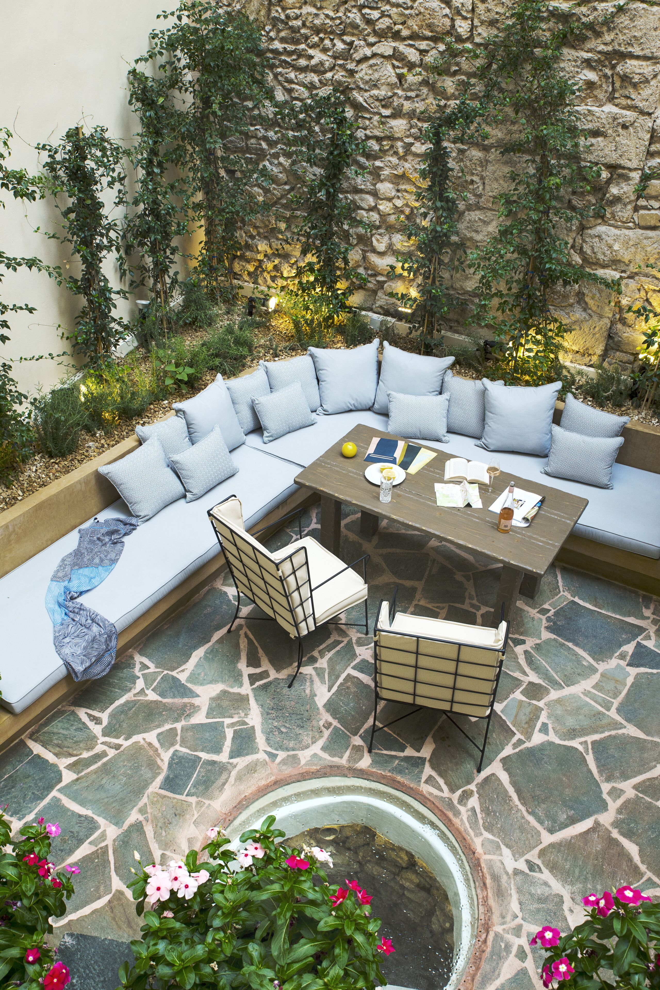 A stone patio with a curved seating area, a table, and chairs.