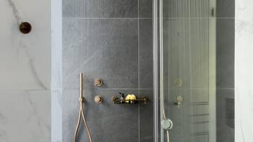 A modern shower with a glass enclosure, a handheld showerhead, and a wall-mounted showerhead.