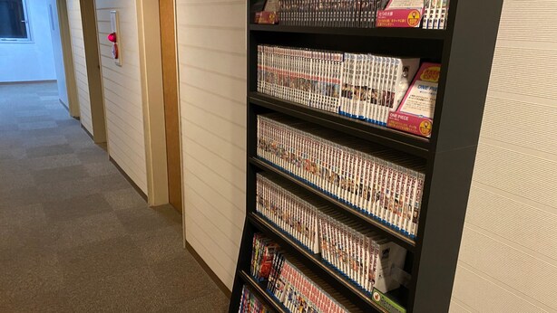 Een gang met een boekenplank vol met manga.