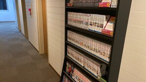 A hallway with a bookshelf filled with manga volumes.