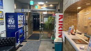Een ontvangstgebied met een blauwe Suntory Coffee Boss automaat, een receptiebalie en een potplant.