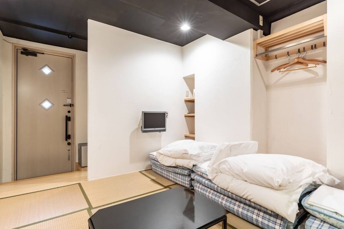 Ein Zimmer mit einem Bett, einem kleinen Tisch, einem Fernseher und einem Kleiderschrank.