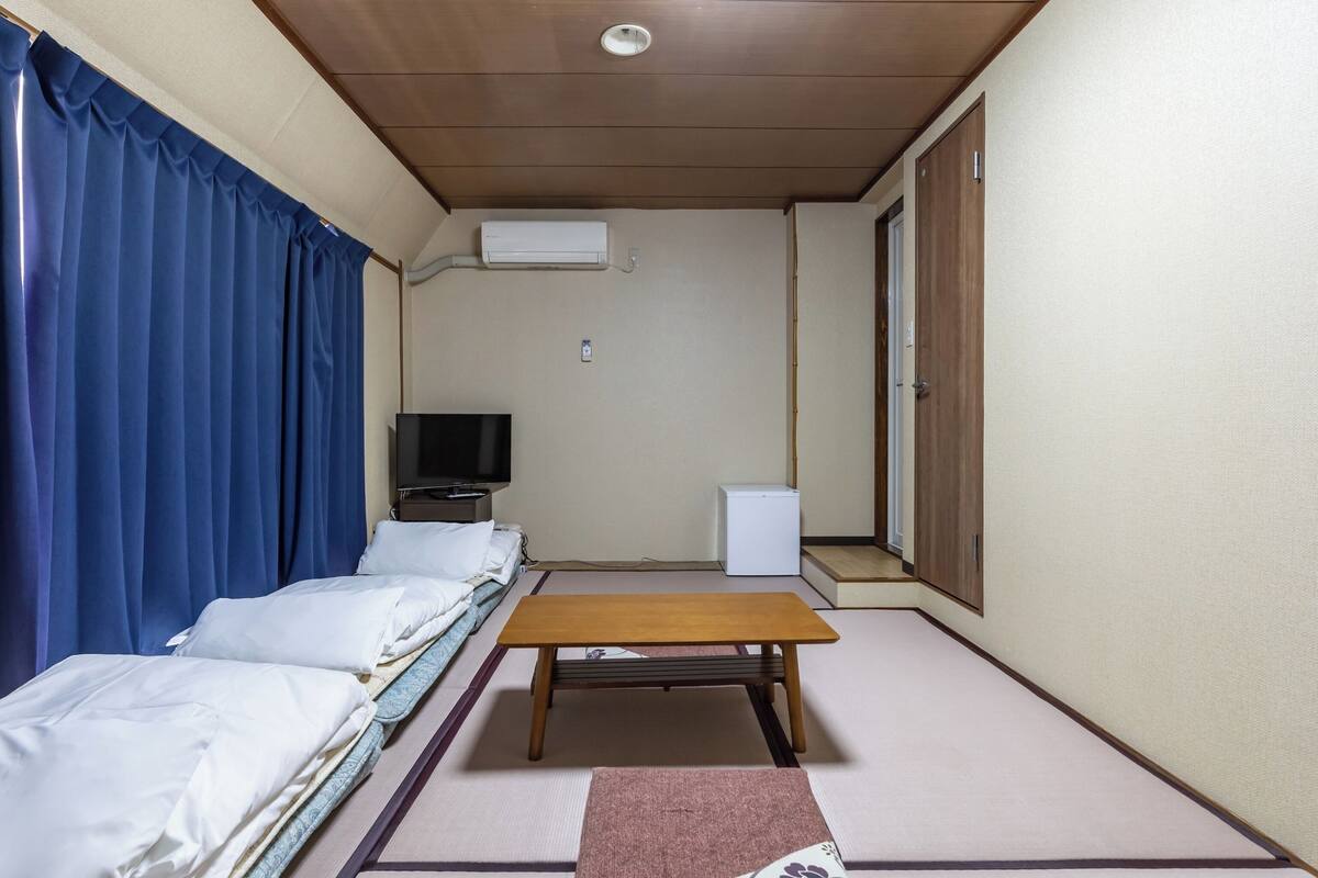 Ein Zimmer mit einem Bett, einem Fernseher, einem kleinen Tisch und einem Schrank.