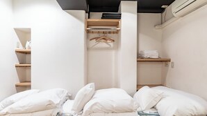A room with a bed, a wardrobe, and a shelf with folded clothes. - Tabist Business Hotel Japan Takamatsu Kagawa (Takamatsu)