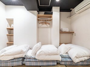 Une pièce comprenant un lit, une armoire et une étagère avec des vêtements pliés.