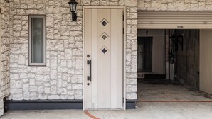 A stone facade with a beige door, a small window, and a garage door. - Tabist Business Hotel Japan Takamatsu Kagawa (Takamatsu)