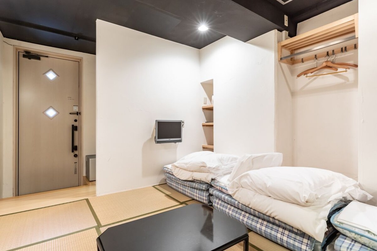 A room with a bed, a small table, a TV, and a wardrobe.
