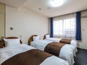 Habitación de hotel con tres camas, una ventana con cortinas azules y una lámpara en el techo.