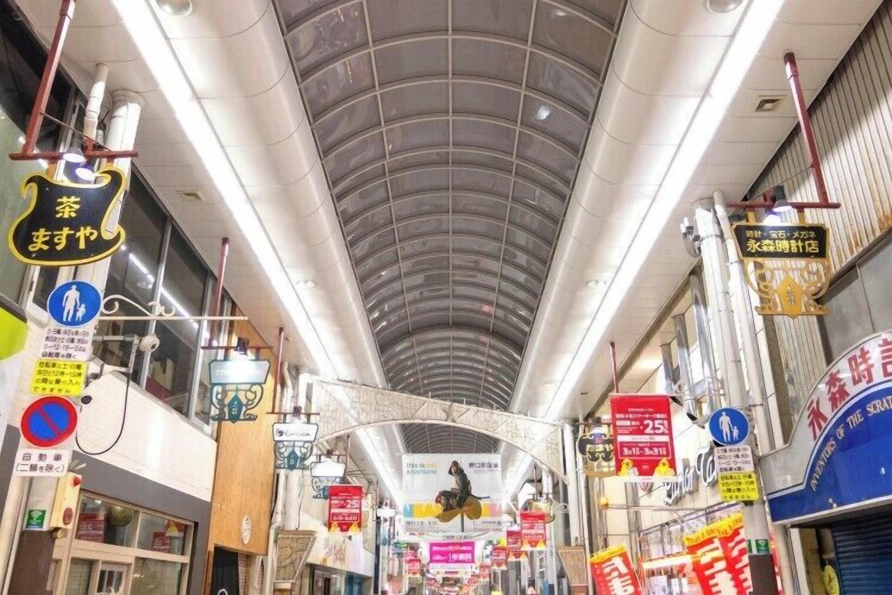 An indoor shopping area with a curved ceiling, various signs, and a central archway.