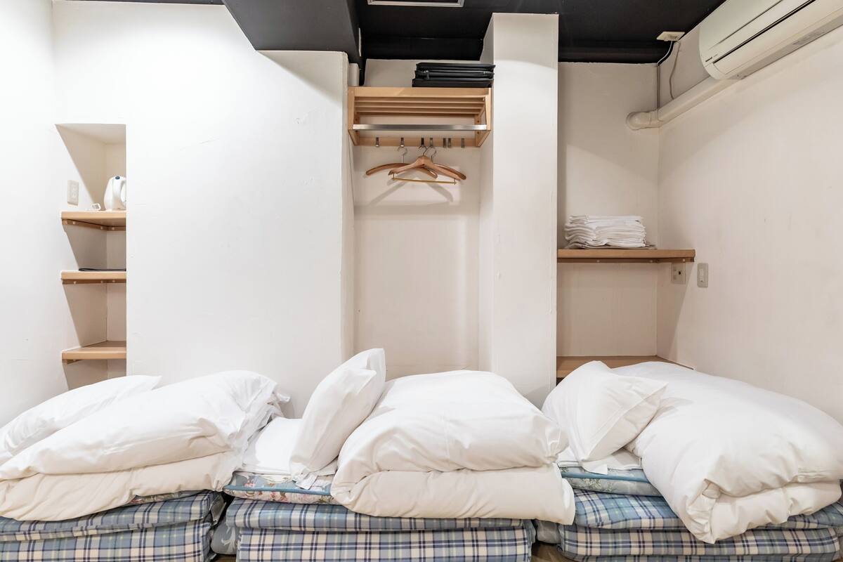 Ein Zimmer mit einem Bett, einem Kleiderschrank und einem Regal mit gefalteter Kleidung.