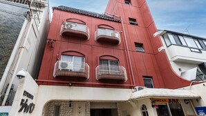 A red building with multiple balconies, a stone facade, and a sign for a business hotel. - Tabist Business Hotel Japan Takamatsu Kagawa (Takamatsu)