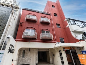 Un bâtiment rouge doté de nombreux balcons, d’une façade en pierre et d’une enseigne indiquant qu’il s’agit d’un hôtel d’affaires.