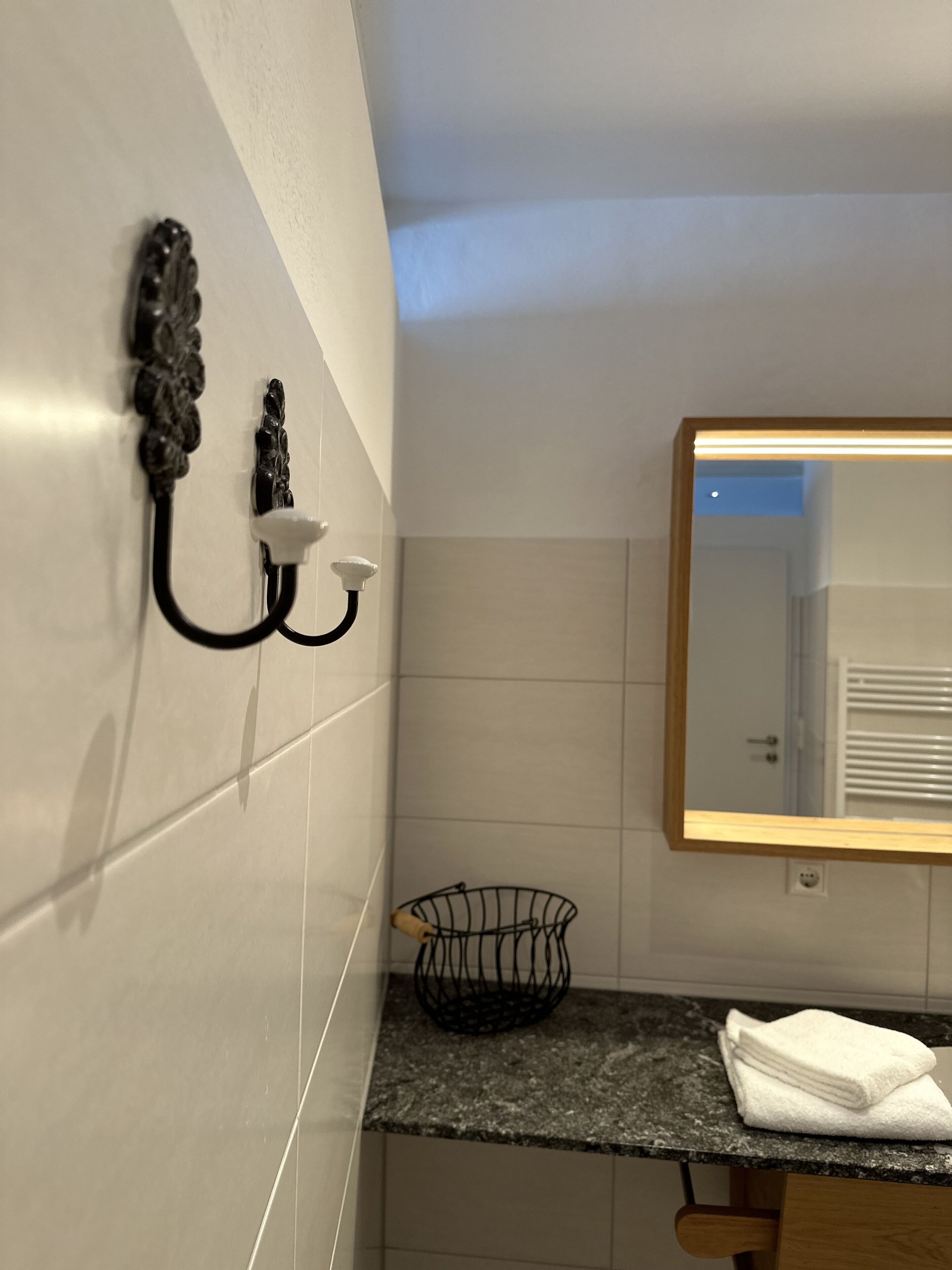 A bathroom with a mirror, a towel rack, and a sink with a towel.