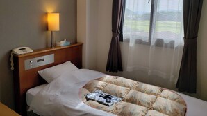 Ein Hotelzimmer mit Bett, Nachttischlampe, Telefon und einem Fenster mit Vorhängen.