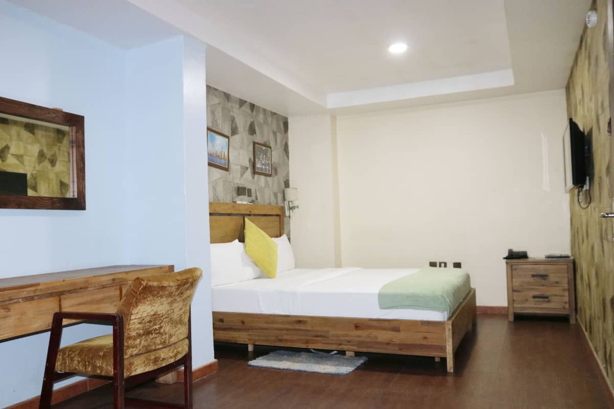 A bedroom with a wooden bed, a desk, and a chair.