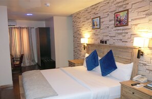 A hotel room with a bed, two bedside lamps, a wooden nightstand, a telephone, and a wall with a brick pattern. - Villa ToscanaHotels (Lagos)