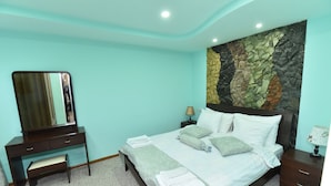 A bedroom with a bed, a dresser, a mirror, a nightstand, and a wall with a stone pattern. - Gayane Hotel (Haghpat)