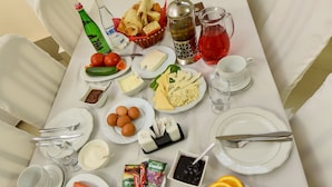 A dining table set with various food items and beverages, surrounded by white chairs. - Gayane Hotel (Haghpat)