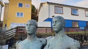 Eine Statue von zwei Personen vor einem Gebäude mit gelb-blauer Fassade.