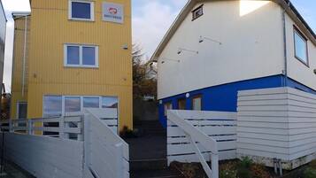 A yellow building with a sign labeled "GUESTHOUSE" and a white building with a blue section and a staircase leading to a door.