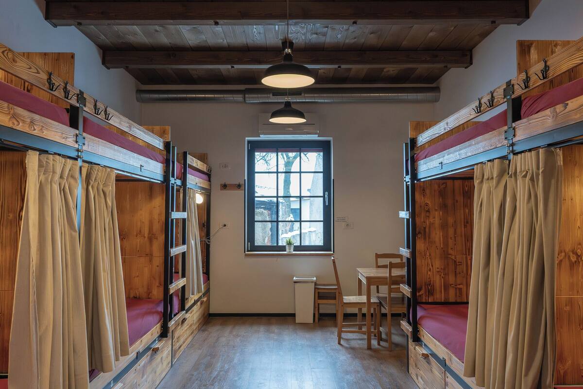 Una habitación con literas de madera, un escritorio y una ventana.