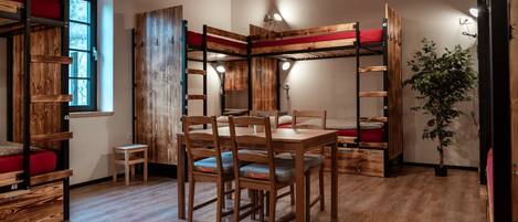 A room with bunk beds, a dining table with chairs, and a small side table.