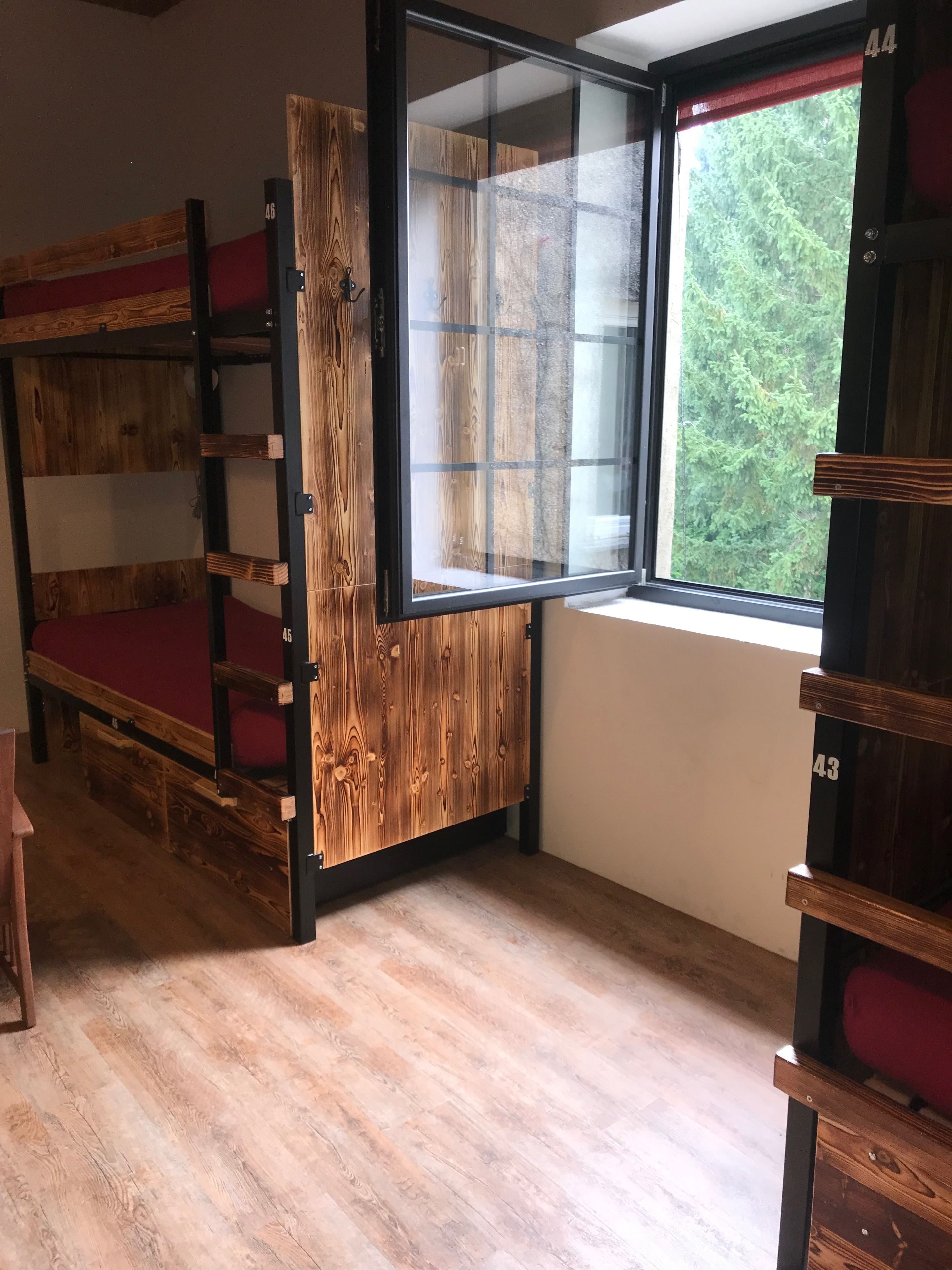 A room with bunk beds, a large window, and a wooden door.