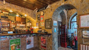 Interior de un pub con paredes de piedra, una barra y varios carteles.