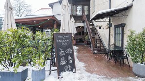 Entrada de un pub con letrero, mesas al aire libre y una escalera que lleva a un nivel superior.
