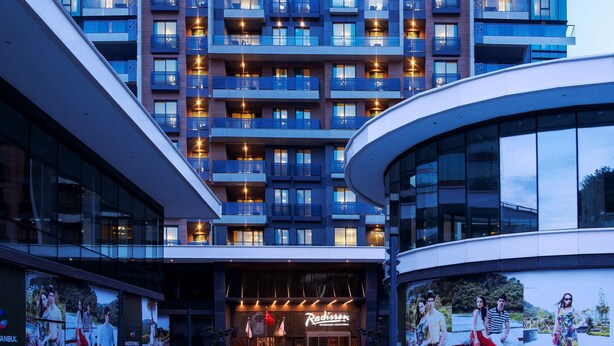Un hôtel moderne à plusieurs étages, doté de balcons, d’une entrée principale et d’un restaurant bien visible.