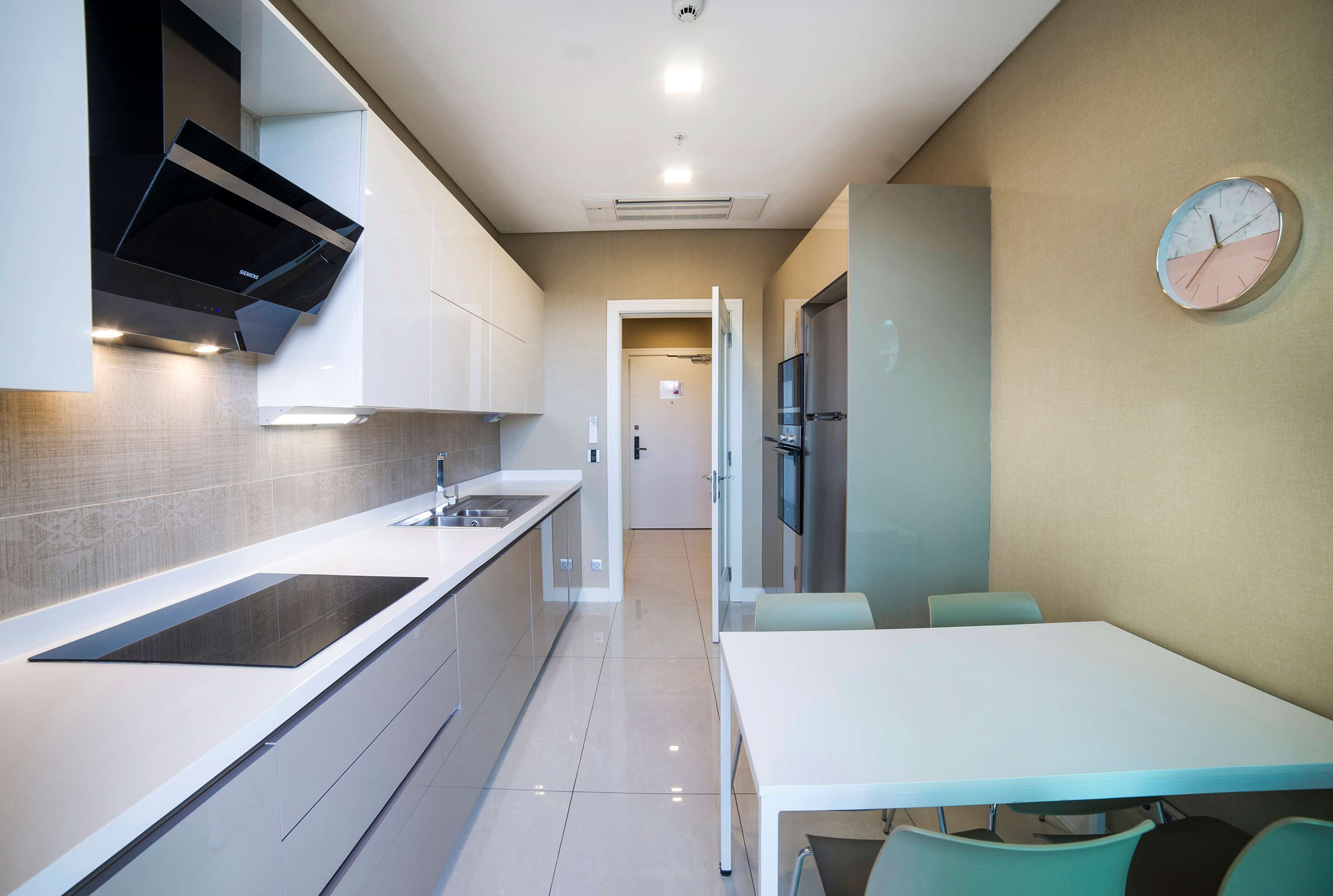 A modern kitchen with a built-in stove, a sink, and a dining area with a table and chairs.