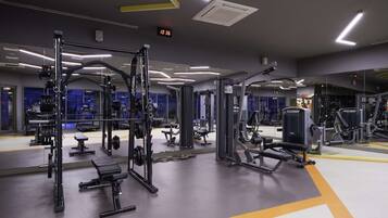 Een moderne fitnessruimte met diverse trainingsapparaten, waaronder gewichtmachines en banken.