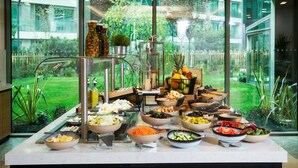 Un buffet bien garni avec une variété de plats, et une vue sur un jardin grâce à de grandes fenêtres.