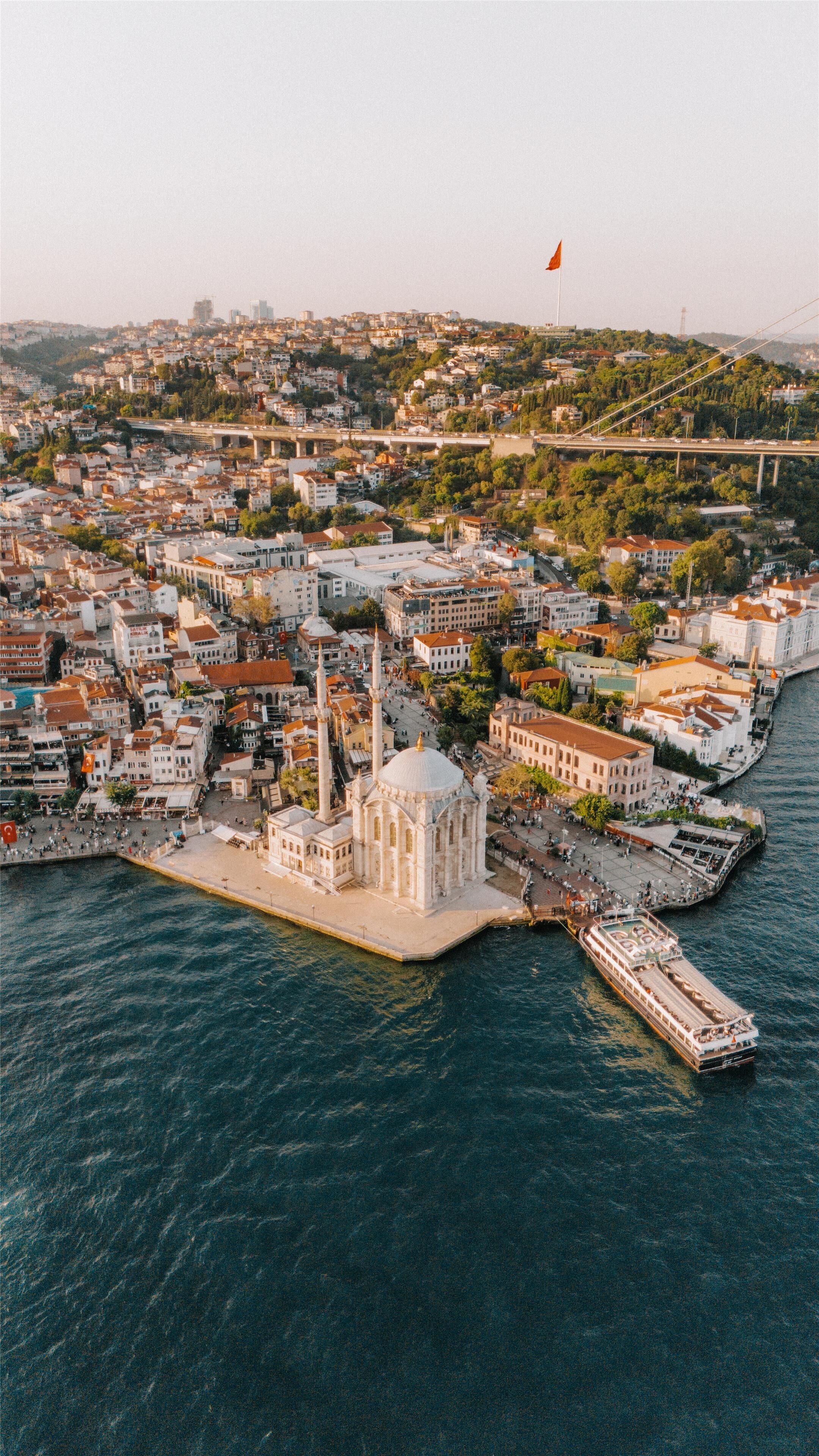 An aerial view of a coastal city with a prominent white-domed building, a bridge, and a river.