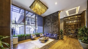 Un vaste espace de vie avec une grande fenêtre, un canapé bleu, une table basse et une bibliothèque.