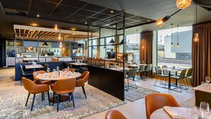 A modern restaurant with a bar area, dining tables, and chairs. - Radisson Hotel Antwerp Berchem (Antwerp)