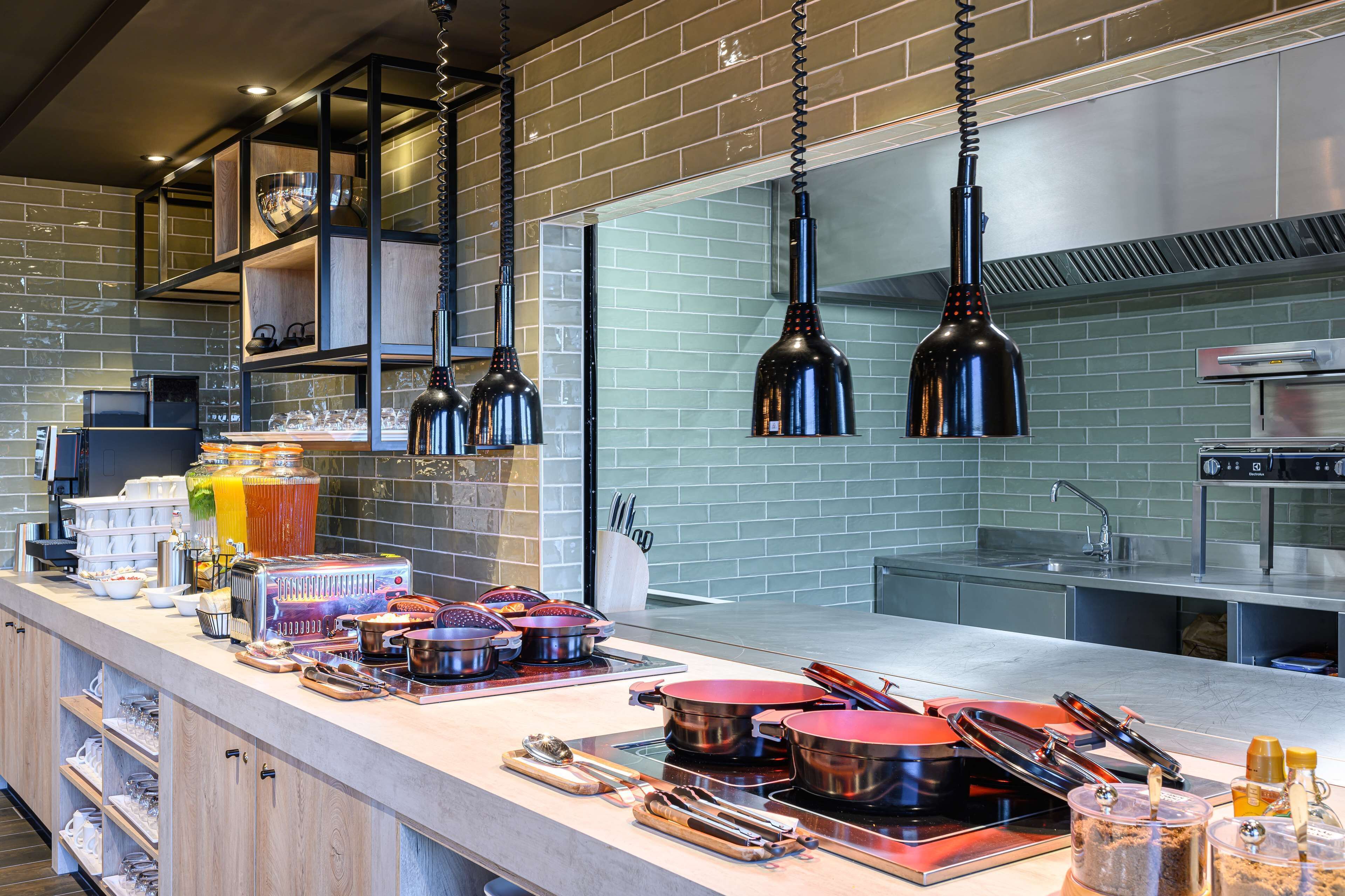 Una cocina moderna con electrodomésticos de acero inoxidable, repisas de madera y lámparas colgantes.