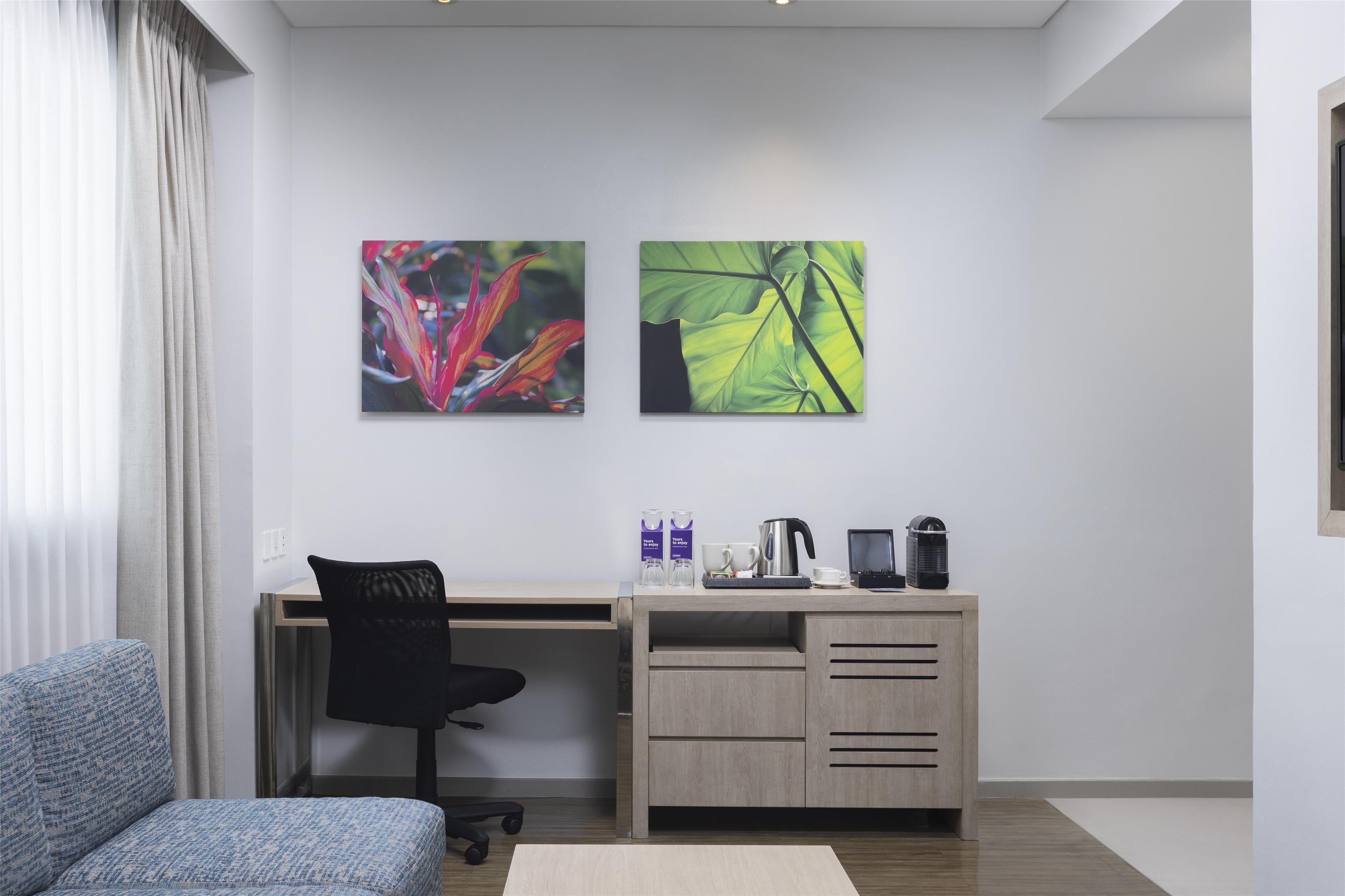 A modern office space with a desk, chair, and two artworks on the wall.