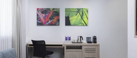 Un espacio de oficina moderno con un escritorio, una silla y dos obras de arte en la pared.