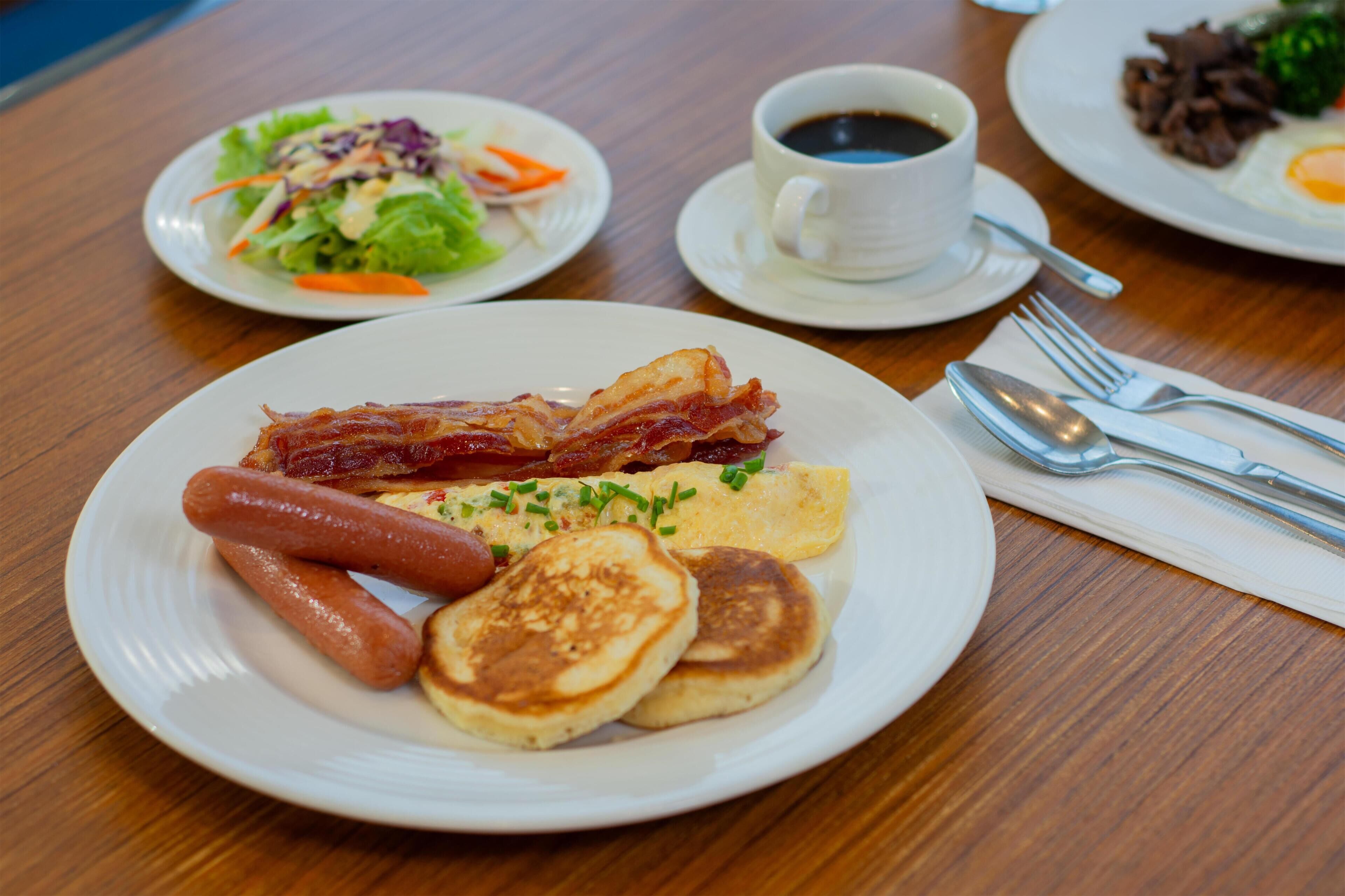 Un plato de desayuno con tocino, salchichas, panqueques y huevos.