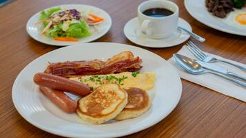 Un plato de desayuno con tocino, salchichas, panqueques y huevos.